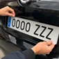 Mecánico instalando una nueva placa de matrícula acrílica en un coche para sustituir la antigua y superar la ITV.