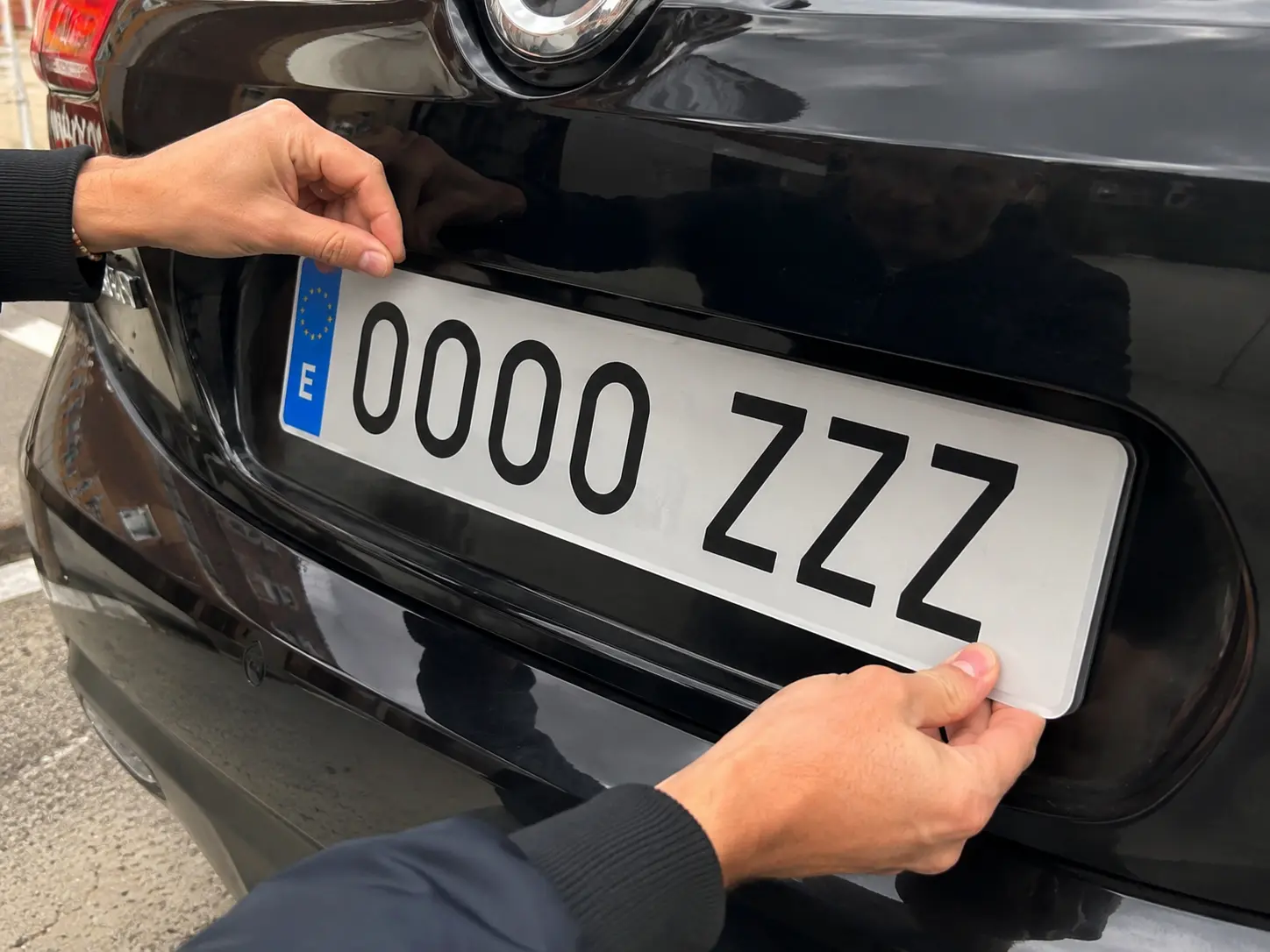 Mecánico instalando una nueva placa de matrícula acrílica en un coche para sustituir la antigua y superar la ITV.